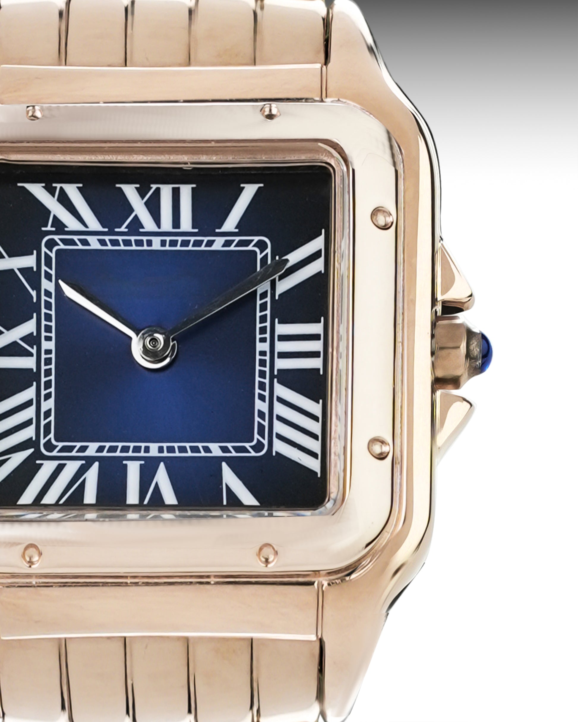 Rose gold watch with blue face and Roman numerals on a gray background