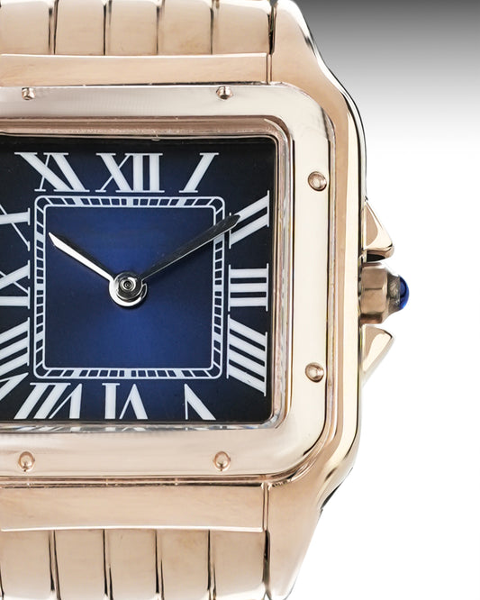 Rose gold watch with blue face and Roman numerals on a gray background